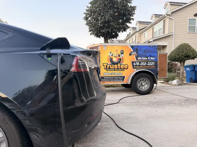 Dark Tesla connected to a charging cable with the Trustee mobile EV charging trailer in a driveway